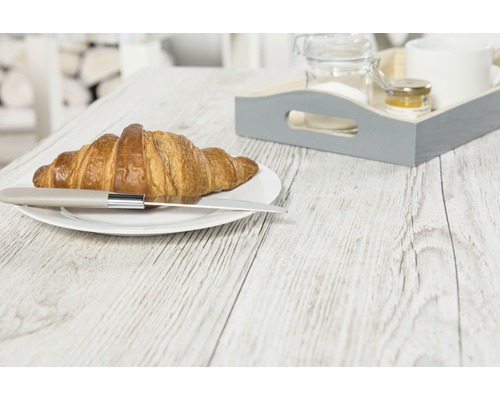 Un croissant cu cuțit pe o farfurie și o tavă pe o masă de lemn