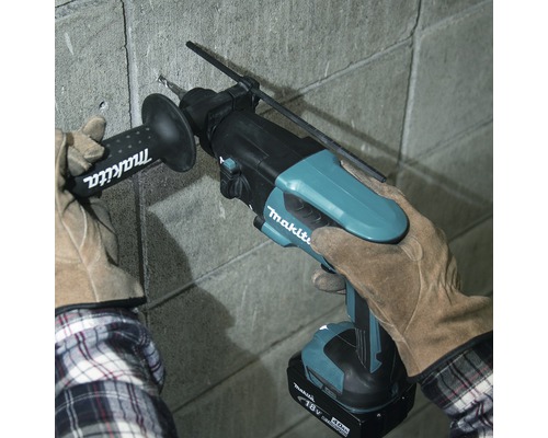 O persoană găurește un perete cu un ciocan rotopercutor Makita.
