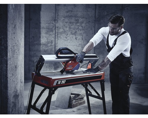 Un bărbat operează o mașină de tăiat faianță TR 202 într-un atelier.