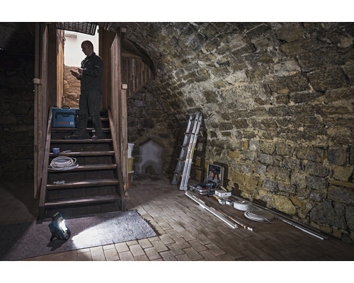 Spațiu de pivniță cu scară de piatră, lampă de lucru, cutie de scule și artizan