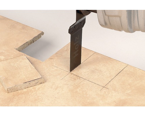 Un ferăstrău oscilant taie o faianță de-a lungul unei linii de creion.