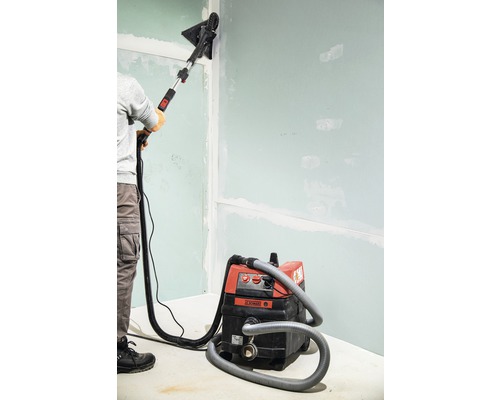 O persoană șlefuiește un perete cu o șlefuitoare pentru gips-carton și un aspirator.