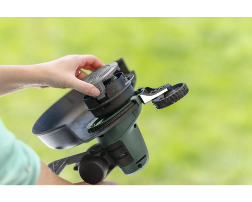 O persoană schimbă bobina unei mașini de tuns iarba.