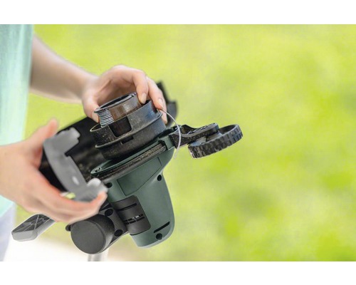 Mâini schimbând bobina unui trimmer de gazon