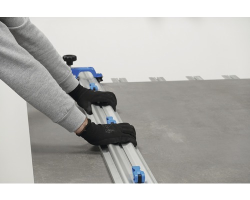 Persoană care folosește un tăietor de plăci pentru a tăia plăci