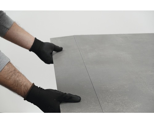 Persoană cu mănuși care așază acoperirea podelei