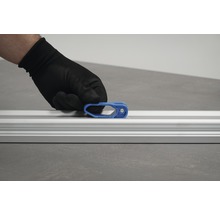 O mână cu mănușă de protecție fixează un glisor albastru pe o șină de aluminiu.