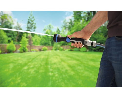 O persoană udă o grădină cu un pistol de pulverizare pentru grădină.