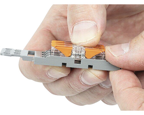 Mâinile unui bărbat conectează un conector de sârmă la o consolă de montare.