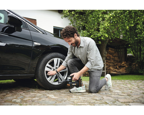 Bărbat umflă o anvelopă auto cu un compresor fără fir