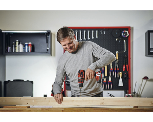 Un bărbat înșurubează șuruburi în lemn cu o șurubelniță fără fir.