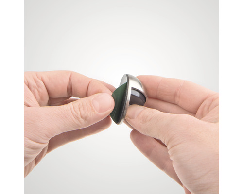 O mână ține un glisor de mobilă cu suprafață de alunecare din pâslă.