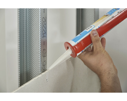 O persoană aplică etanșant pe o placă de gips-carton