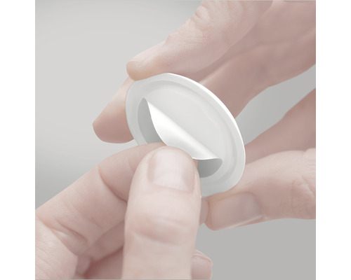 O mână dezlipește folia de protecție de pe un buton de mobilă.