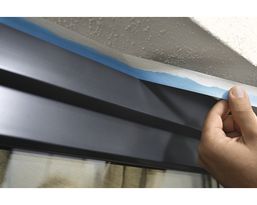 Aplicarea benzii de mascare pe o fereastră înainte de vopsire.