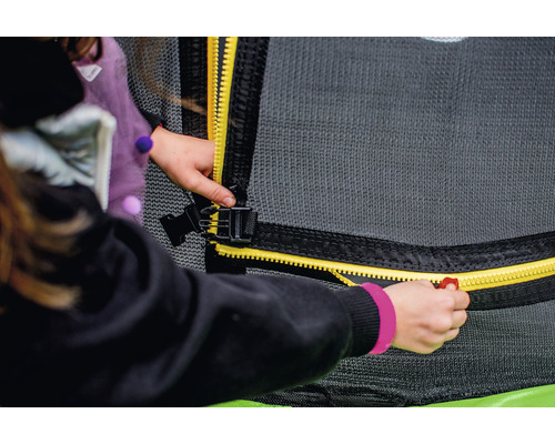 Un copil închide fermoarul plasei de siguranță a trambulinei.