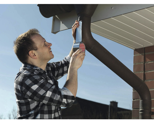 Un bărbat repară o jgheabă cu bandă de etanșare.