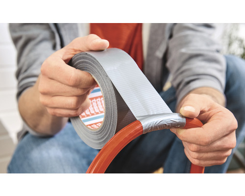 Persoană reparând un furtun cu bandă adezivă din țesătură