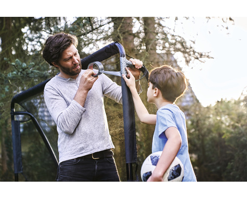 Tatăl și fiul repară o poartă de fotbal cu bandă adezivă în grădină.