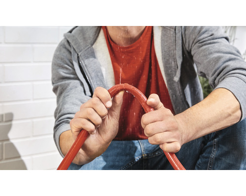 O persoană ține un furtun de grădină care curge.