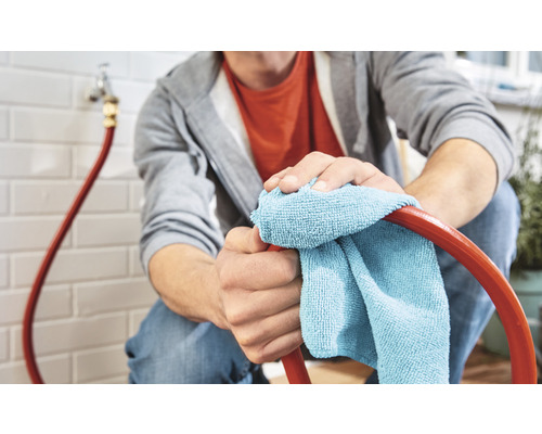 O persoană curăță un furtun de grădină cu o cârpă.