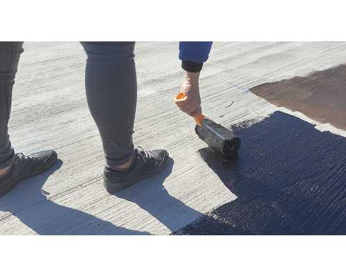 O persoană aplică un strat pe o suprafață cu o rolă de vopsit.