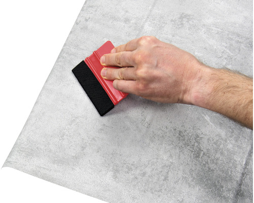 Mână cu racletă care aplică folie cu model de piatră