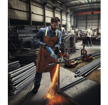 Un muncitor taie o țeavă metalică cu un polizor unghiular într-un atelier.
