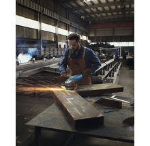 Un bărbat în haine de lucru folosește un polizor unghiular pe o bucată de metal într-un atelier.
