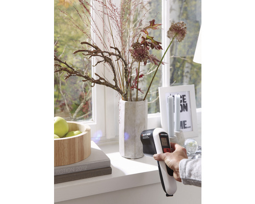 O persoană măsoară temperatura la fereastră cu termometrul cu infraroșu de la Black and Decker