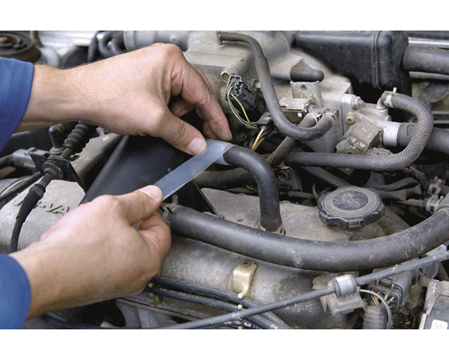 O persoană repară un furtun auto cu o bandă de reparații.