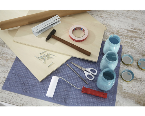 Aranjament de unelte și materiale pentru proiecte de bricolaj, incluzând lemn, ciocan, șuruburi, bandă adezivă și borcane vopsite.