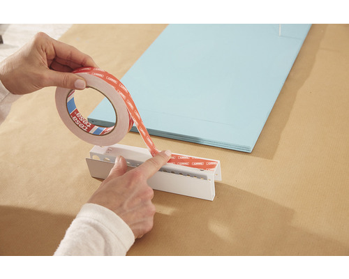 Aplicarea de bandă dublu adezivă pe un profil de montaj alb.