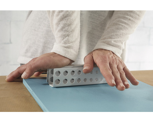 Persoană care utilizează un bloc de șlefuire pe o scândură de lemn albastră