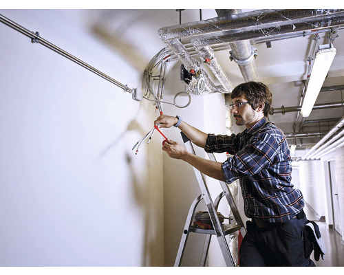 Electrician pe o scară instalând cabluri electrice