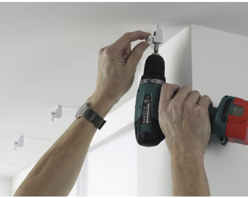 Montarea unei șine de perdea cu o șurubelniță cu acumulator pe tavan.