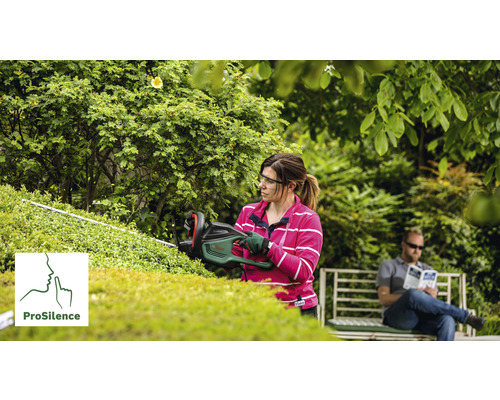 Femeie tăind un gard viu cu o foarfecă de gard viu, cu un bărbat pe o bancă în fundal. Logo ProSilence