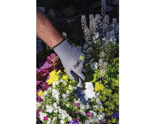 Persoană cu mănuși de grădinărit și plantator plantând flori
