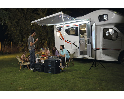 Scenă cu autocaravană, persoane și surse de alimentare portabile pentru activități de camping în aer liber