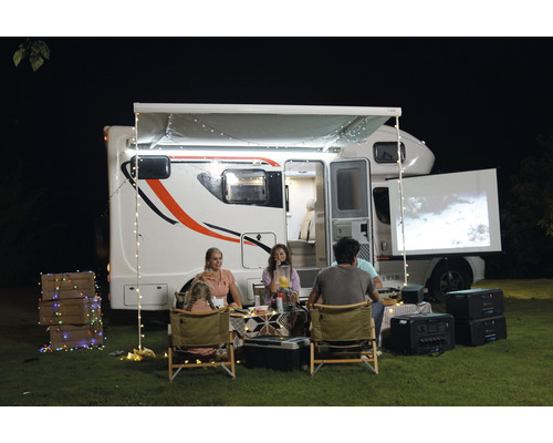 O familie se bucură de o seară de film în aer liber cu o rulotă, un proiector și un ecran.