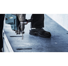 Un bărbat găurește o placă de beton cu un ciocan rotopercutor.
