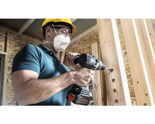 Un bărbat găurește lemn cu o șurubelniță electrică fără fir.