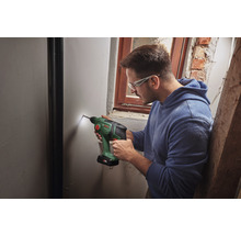 Un bărbat găurește un perete cu o mașină de găurit fără fir.