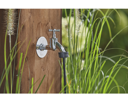 Robinet de grădină cu robinet de apă și racord de furtun pe un perete de lemn