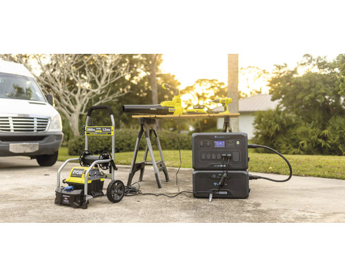 Aspirator Ryobi de înaltă presiune, suflantă de frunze și șurubelniță cu acumulator împreună cu o stație de alimentare Bluetti pe o alee.