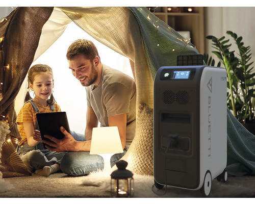 Tată și fiică cu tabletă într-un cort în interior, alături de o centrală electrică mobilă Bluetti