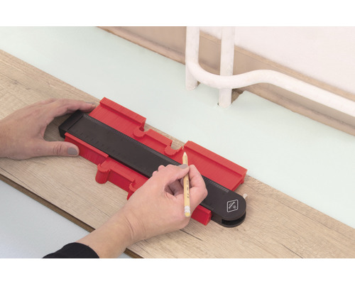 O persoană folosește un șablon de contur pentru a trasa pe o podea din lemn