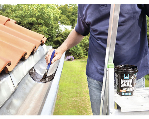 Bărbat etanșează jgheabul cu un strat de cauciuc