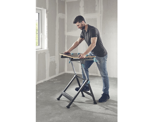 Un bărbat folosește o masă de lucru pliabilă într-o cameră.