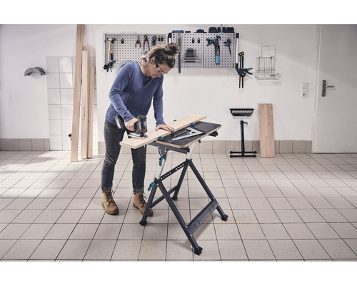 Femeie taie lemn pe un banc de lucru cu un fierăstrău vertical într-un atelier